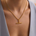 Load image into Gallery viewer, A gold chain necklace with a toggle bar pendant, worn on a model's neck over a light gray sleeveless top.
