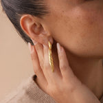 Load image into Gallery viewer, Close-up of a person wearing a gold earring with a neutral background