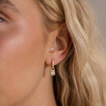 Load image into Gallery viewer, Close-up of a person wearing a gold hoop earring with a blurred background