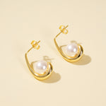 Load image into Gallery viewer, Gold earrings with pearl drops on a beige background