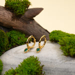 Load image into Gallery viewer, Gold hoop earrings with green gemstones on a stone surface with moss