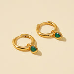 Load image into Gallery viewer, Gold hoop earrings with green stones on a beige background