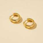 Load image into Gallery viewer, Gold hoop earrings with star and moon designs on a beige background