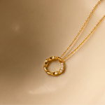 Load image into Gallery viewer, Gold necklace with a circular pendant on a beige background