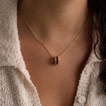 Load image into Gallery viewer, Gold necklace with a hexagonal pendant worn by a person in a textured white cardigan.