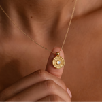 Load image into Gallery viewer, Gold plated necklace with a pendant held by a hand against a brown background