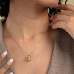 Load image into Gallery viewer, A close-up of a model wearing an elegant gold necklace from Zewory Jewellery, featuring a unique barrel pendant. The pendant's central pavƩ crystal band sparkles against her skin, showcasing a sophisticated piece of fashion jewellery.