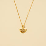 Load image into Gallery viewer, A clean, minimalist product shot of a gold seashell necklace on a neutral cream background. The image clearly displays the detailed, ribbed texture of the scallop shell pendant and its delicate chain.