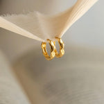 Load image into Gallery viewer, Two gold hoop earrings hanging from a wooden hook against a neutral background