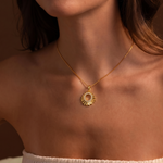 Load image into Gallery viewer, Woman wearing a gold necklace with a sunflower pendant against a brown background