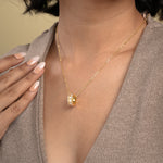 Load image into Gallery viewer, A close-up of a model wearing an elegant gold necklace from Zewory Jewellery. The unique barrel pendant, featuring a white mother-of-pearl honeycomb pattern and a sparkling pavé crystal band, is showcased against her neutral-coloured top.