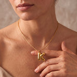 Load image into Gallery viewer, A close-up of a model wearing a delicate gold chain necklace with a polished anchor pendant, with her hand resting near the necklace.