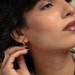 Load image into Gallery viewer, A close-up of a model wearing a modern, wavy gold huggie hoop earring from Zewory Jewellery. The small, sculptural hoop elegantly hugs her earlobe, showcasing a chic and minimalist accessory perfect for everyday style.
