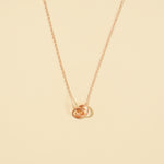Load image into Gallery viewer, An elegant rose gold necklace from Zewory Jewellery, featuring a delicate double interlocking rings pendant. This minimalist piece is displayed on a smooth beige plain background.