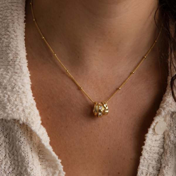 Close-up of a person wearing a gold necklace with a pendant.