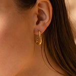 Load image into Gallery viewer, Close-up of a person wearing a gold hoop earring with a blurred background

