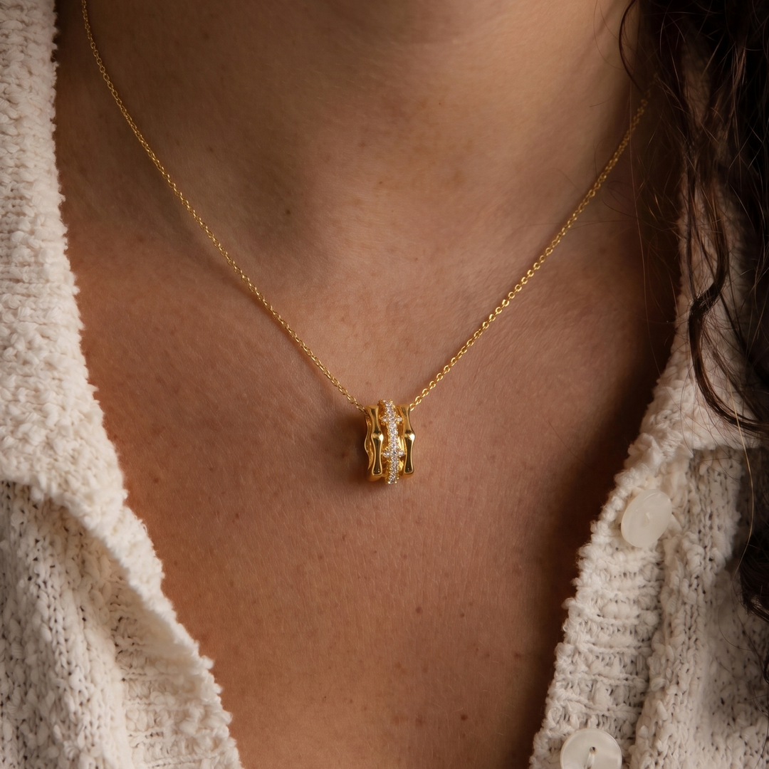 Close-up of a person wearing a gold plated necklace with a pendant.
