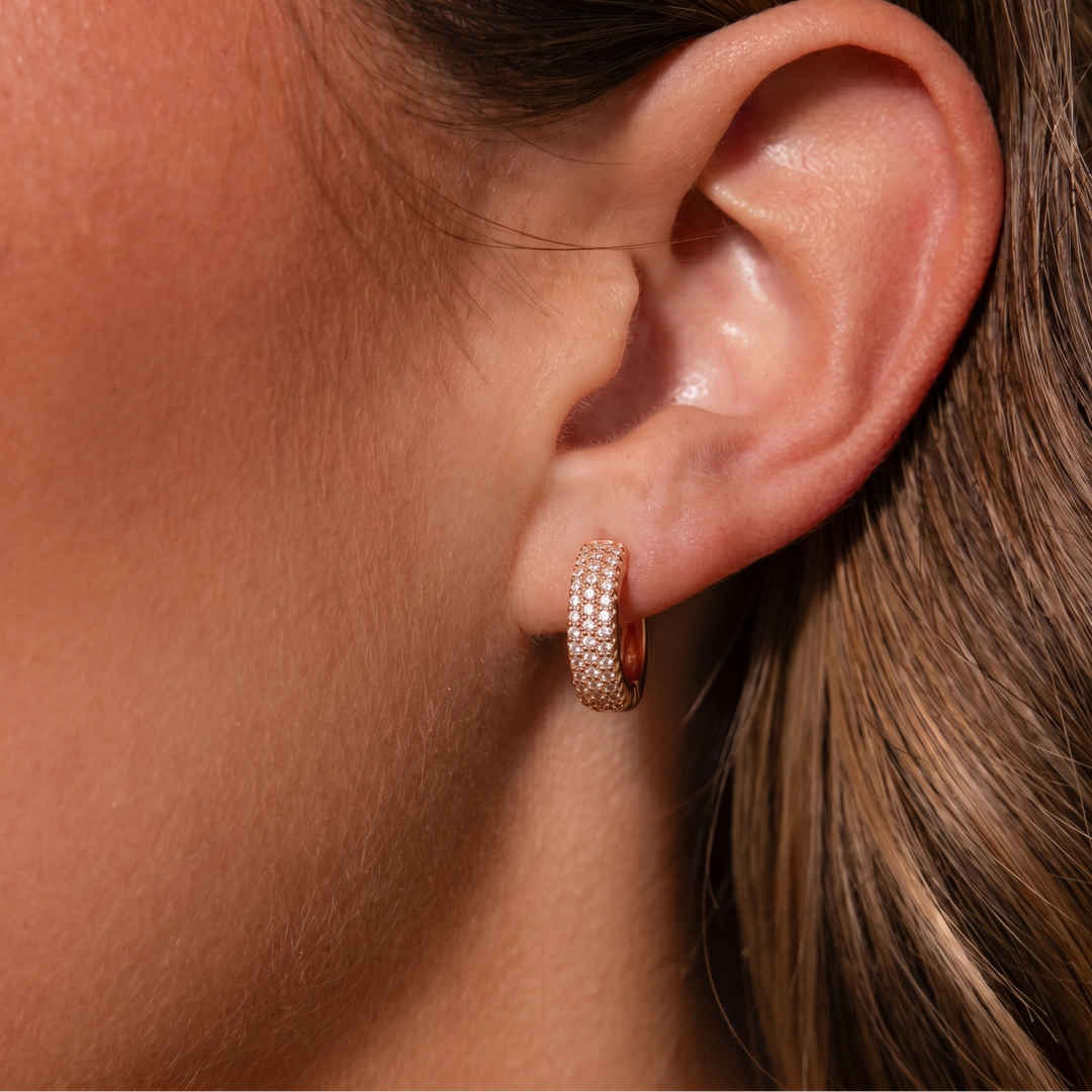 Close-up of an ear wearing a gold hoop earring with a blurred background