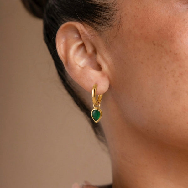 Close-up of an ear wearing a gold hoop earring with a star design.