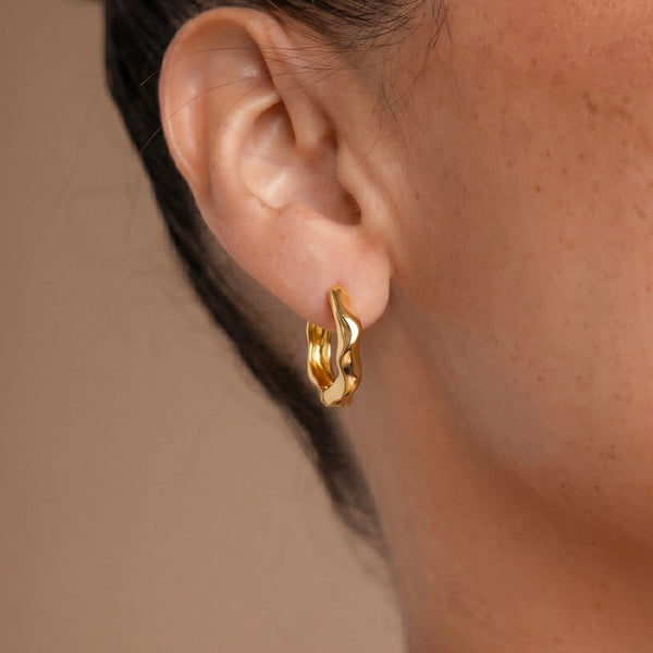 Close-up of an ear wearing a gold hoop earring with a star design.