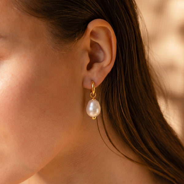 Close-up of an ear wearing a pearl earring with a blurred background
