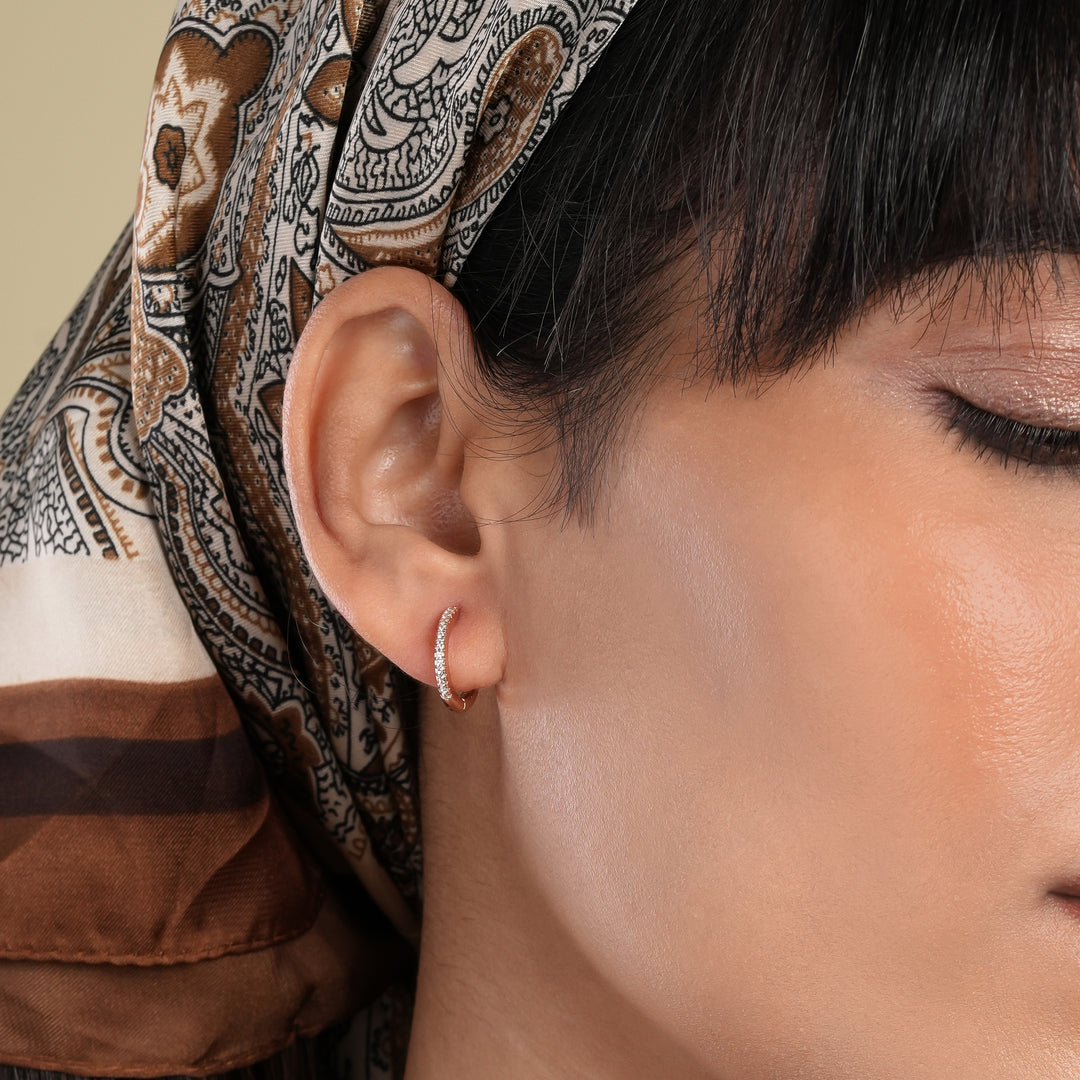 Close-up of an ear with a hoop earring, wearing a patterned headscarf.
