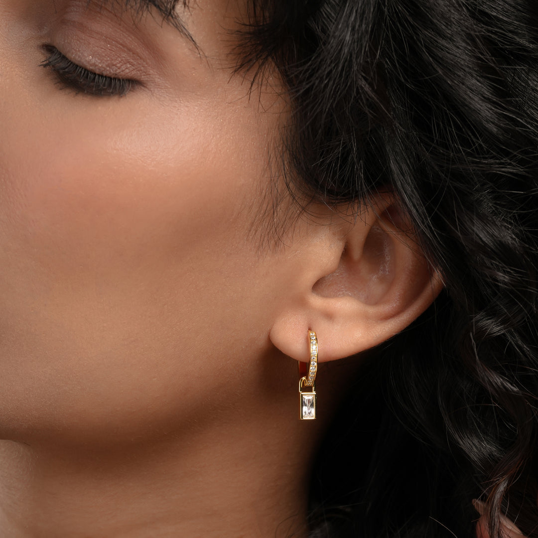 Close-up of a woman wearing gold hoop earrings with a dark background
