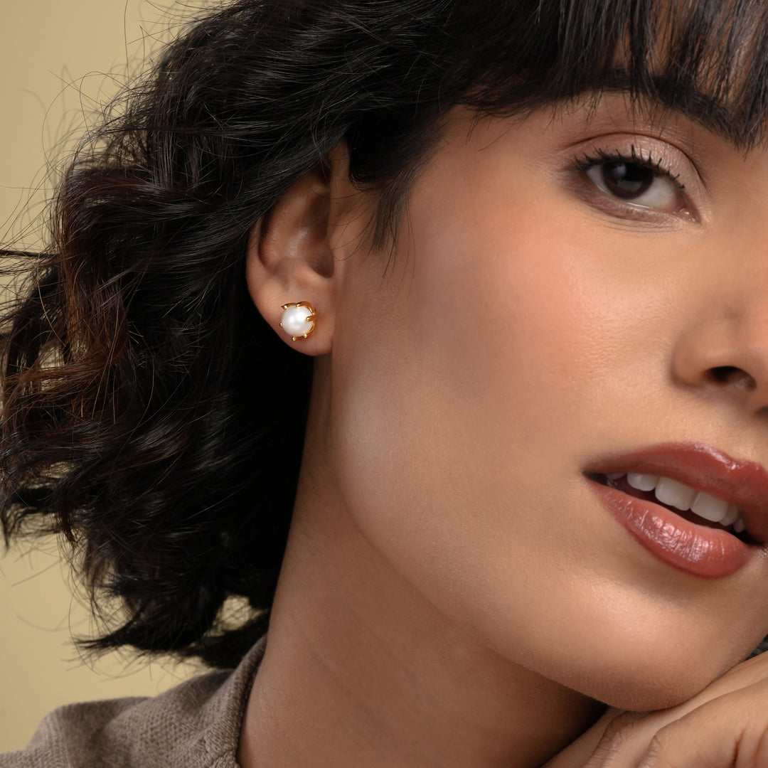 Close-up of a woman wearing pearl earrings with a neutral background