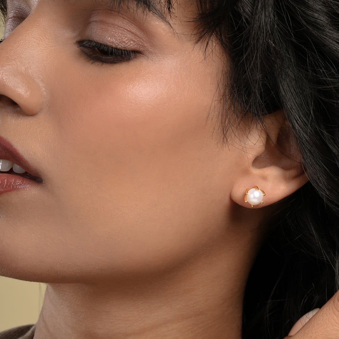 Close-up of a woman wearing pearl earrings with a neutral background