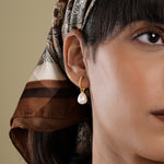 Load image into Gallery viewer, Close-up of a person wearing a pearl earring with a patterned headscarf on a beige background
