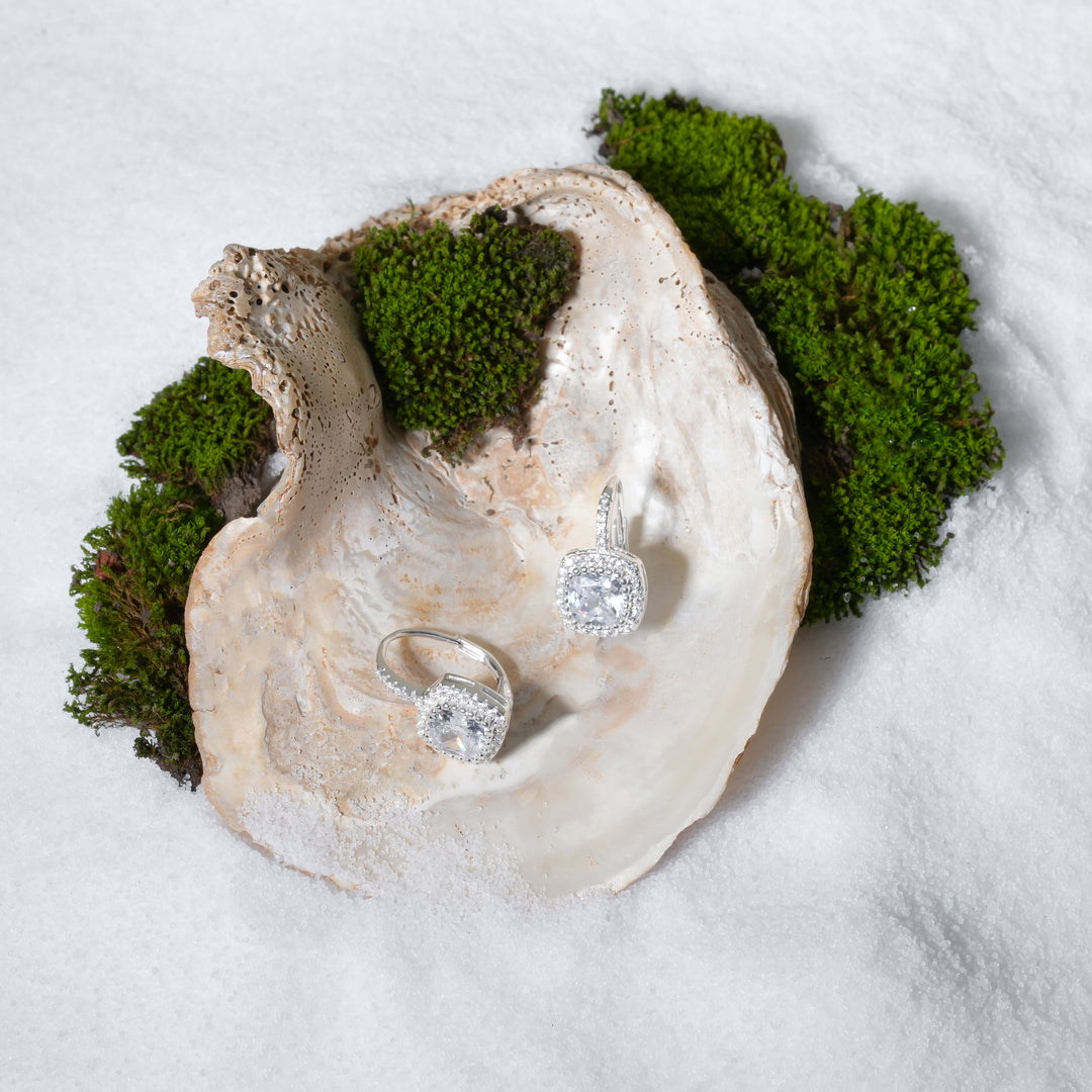 Diamond ring and earrings in an oyster shell with moss on a white background