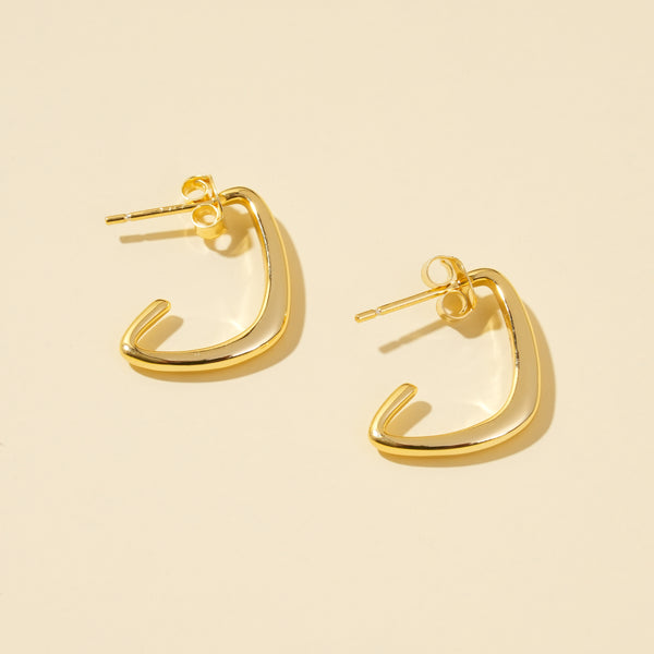 Gold hoop earrings on a beige background