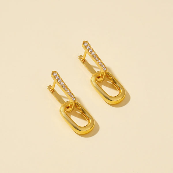Gold earrings with diamond accents on a beige background