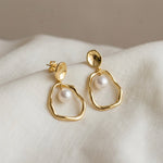 Load image into Gallery viewer, Gold earrings with pearls on a white fabric background
