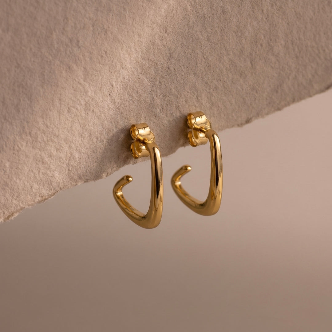 Gold hoop earrings on a textured beige surface