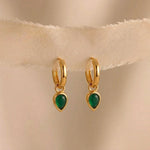 Load image into Gallery viewer, Gold hoop earrings with green gemstones on a beige fabric background

