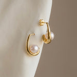Load image into Gallery viewer, Gold hoop earrings with pearl centers on a neutral background
