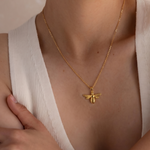 Load image into Gallery viewer, Gold necklace with a bee pendant worn by a person in a white top.
