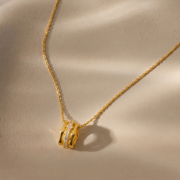 Gold necklace with a diamond pendant on a beige background