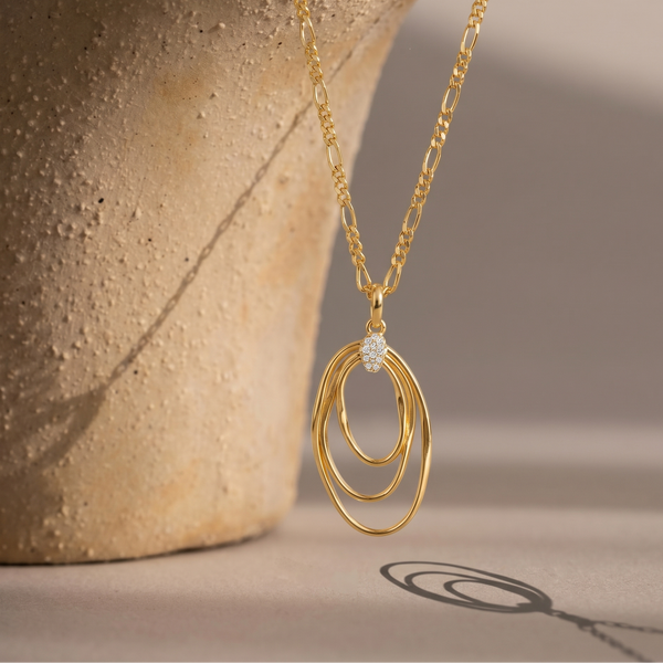 Gold necklace with a diamond pendant on a textured surface