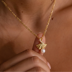 Load image into Gallery viewer, Gold necklace with a fan-shaped pendant and pearl held by a hand against a neutral background
