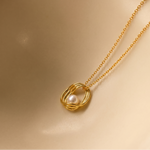 Load image into Gallery viewer, Gold necklace with a pearl pendant on a beige background
