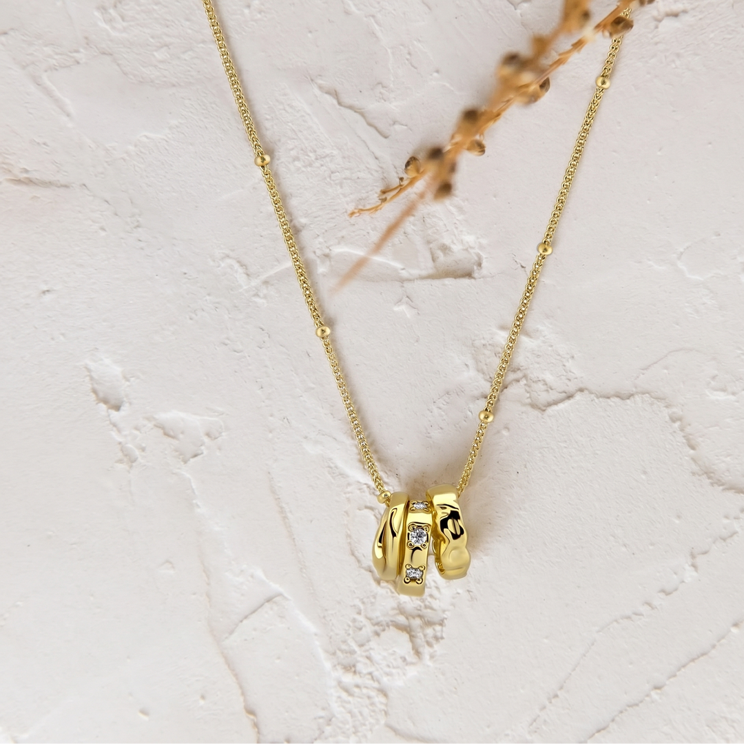 Gold necklace with a pendant on a light marble background