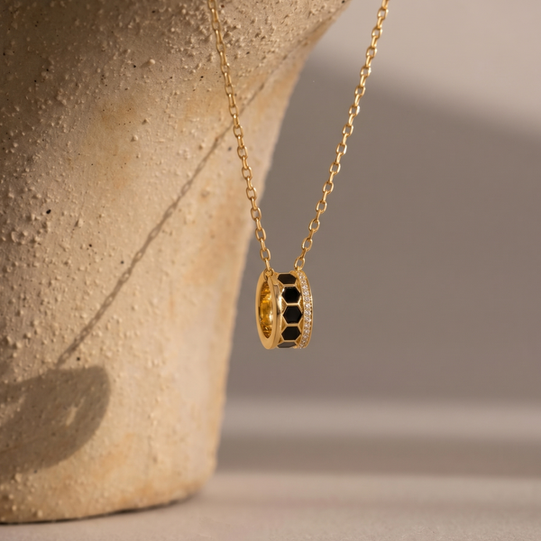 Gold necklace with a pendant on a textured surface