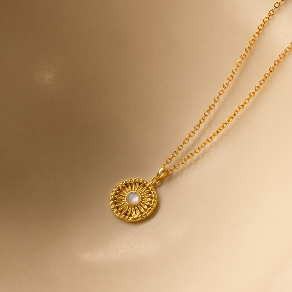 Gold plated necklace with a circular pendant on a beige background