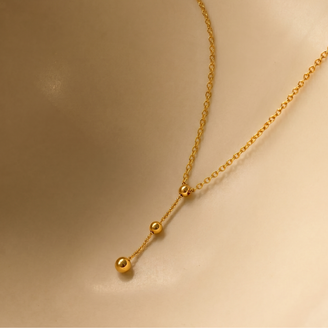 Gold plated  necklace with small beads on a beige background