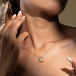 Load image into Gallery viewer, A close-up of a model wearing an elegant gold and pearl necklace from Zewory Jewellery. The modern, sculptural cage pendant with a nestled pearl is showcased in dramatic lighting, resting gracefully in the hollow of her throat.
