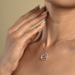 Load image into Gallery viewer, A close-up of a model wearing a sparkling two-tone interlocking hearts necklace from Zewory Jewellery. The romantic pendant, featuring silver and rose gold hearts covered in pavé crystals, rests elegantly against her skin, making it an ideal anniversary or special occasion gift.
