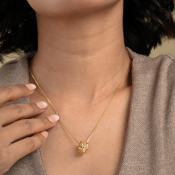 A close-up of a model wearing an elegant gold necklace from Zewory Jewellery, featuring a unique barrel pendant. The pendant's central pavé crystal band sparkles against her skin, showcasing a sophisticated piece of fashion jewellery.
