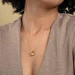 Load image into Gallery viewer, A close-up of a model wearing an elegant gold necklace from Zewory Jewellery. The unique barrel pendant, featuring a modern black honeycomb pattern bordered by sparkling pavé crystals, is showcased against her neutral-coloured top.


